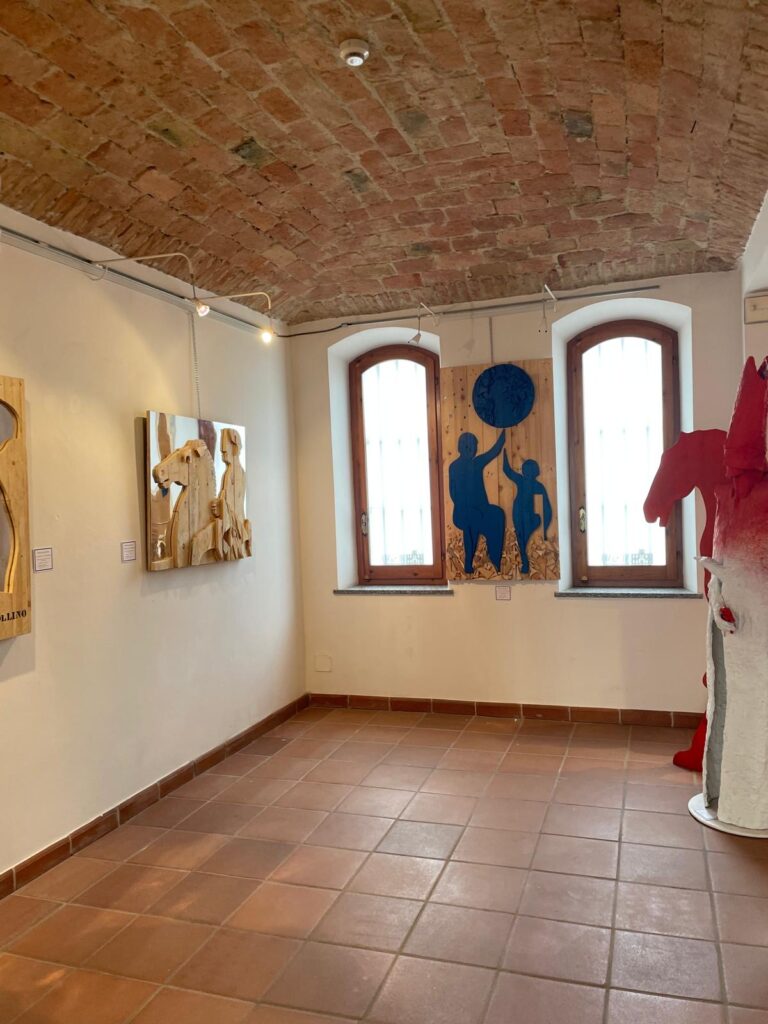 Sala espositiva con opera del cavaliere ligneo e opera raffigurante figure e globo